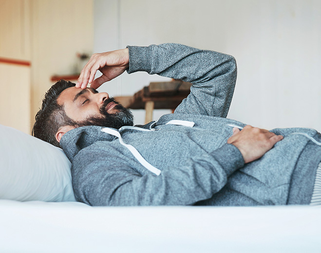 Man resting on bed feeling unwell
