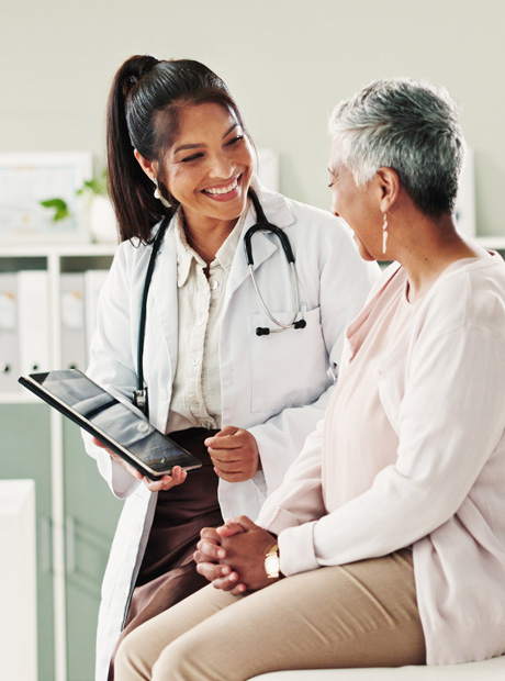 A doctor holds a tablet computer and discusses medical care options with a patient