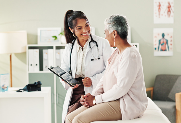 A doctor holds a tablet computer and discusses medical care options with a patient