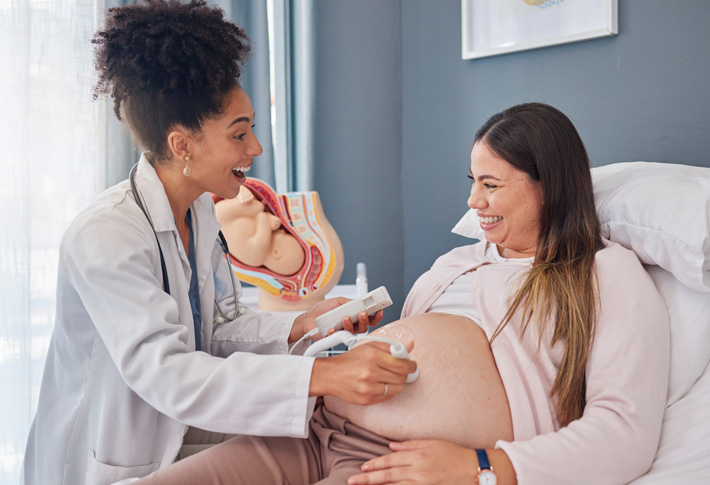 Doctor using fetal Doppler on pregnant abdomen
